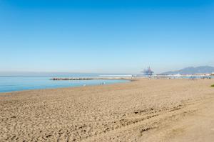 a sandy beach with a pier in the water at Villa Amalia Suites Malaga in Málaga