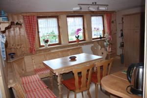 kuchnia z drewnianym stołem i krzesłami oraz oknami w obiekcie Ferienwohnung Familie Harseim w mieście Ruhla