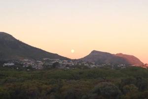 a sunset over a city with mountains in the background at Selkie - Two Restful Studio Apartments near Noordhoek Beach & Restaurants in Noordhoek