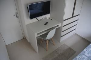 科蒂亞的住宿－Apartamento Completo em Cotia - SP，一张带电视和椅子的白色书桌