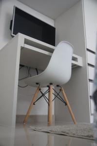 une chaise blanche assise sous un bureau avec un écran d'ordinateur dans l'établissement Apartamento Completo em Cotia - SP, à Cotia