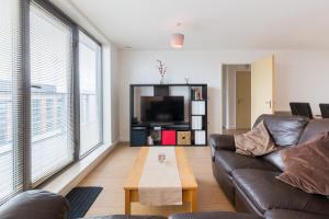 a living room with a leather couch and a tv at City Centre Penthouse in Birmingham