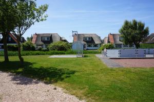 a row of houses in a yard with grass at Buitenplaats 78 in Callantsoog