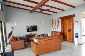 sala de estar con muebles de cuero y TV de pantalla plana en Ngalas Rest 101, en Hectorspruit