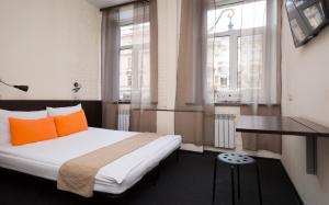 a bedroom with a bed with orange pillows and a window at Station Hotel M19 in Saint Petersburg