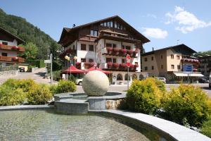 a building with a fountain in front of a building at Hotel Eccher 3 stelle Superior in Mezzana