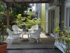 une terrasse couverte avec des chaises blanches et une table. dans l'établissement Residence Virginie, à Saint-Leu