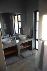 a bathroom with two sinks and two mirrors at Ngalas Rest Mjejane Game Reserve in Hectorspruit +15 photos