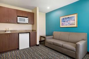 a living room with a couch and a kitchen at Baymont by Wyndham Evansville East in Evansville