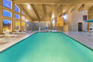 a large swimming pool in a large room with tables and chairs at AmericInn by Wyndham Rhinelander in Rhinelander