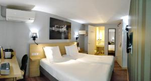 パリにあるベスト ウェスタン ホテル オペラ ドルーオのベッドルーム(白い大型ベッド1台、デスク付)