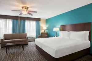 a hotel room with a bed and a chair at Baymont by Wyndham Evansville East in Evansville
