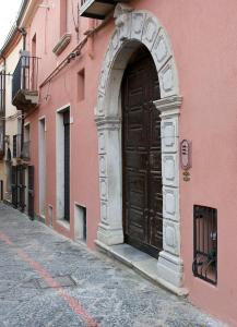 una gran puerta de madera en el lateral de un edificio rosa en B&B La Cuntana, en Potenza