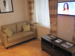 a living room with a couch and a flat screen tv at Mabledon Court Hotel in London