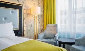 a bedroom with a bed and a chair and a lamp at Thon Hotel Opera in Oslo