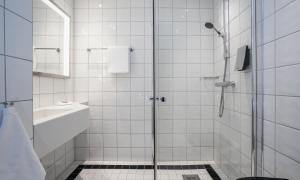 a white bathroom with a shower and a sink at Thon Hotel Opera in Oslo