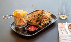 a sandwich on a black plate with chips and sauce at Thon Hotel Opera in Oslo