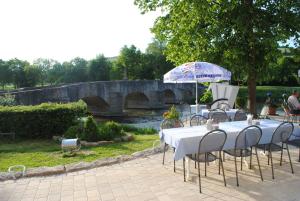 a table with chairs and an umbrella next to a bridge at Landgasthof zum Hirschen in Tauberrettersheim