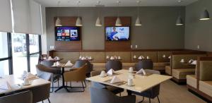 a dining room with tables and chairs and a tv at Wyndham Garden Ft Lauderdale Airport & Cruise Port in Dania Beach