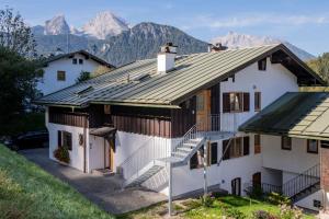 ein weißes Haus mit Bergen im Hintergrund in der Unterkunft Ferienwohnung Hirscheck in Schönau am Königssee