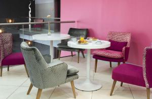 Citadines City Centre Lille في ليل: غرفة طعام مع طاولة بيضاء وكراسي أرجوانية