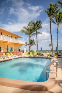 a large swimming pool with chairs and palm trees at Windjammer Resort and Beach Club in Fort Lauderdale