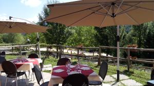 grupa stołów z parasolami na patio w obiekcie Agriturismo Monte Del Re w mieście San Pietro al Natisone