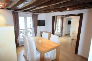 a dining room with a wooden table and white chairs at Superbe Appartement in Paris