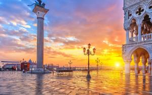 uma praça da cidade com um monumento em frente a um pôr-do-sol em Hotel Mercurio em Veneza