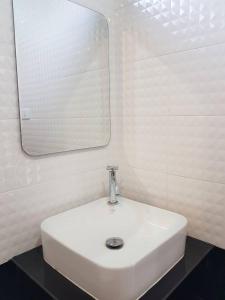 a white sink in a bathroom with a mirror at Beloft Hotel in Nakhon Si Thammarat