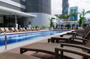a swimming pool with lounge chairs and a hotel at Riu Plaza Panamá in Panama City