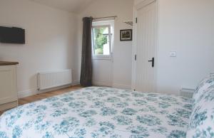 a bedroom with a bed with a blue and white blanket at The Stables at Ballygraffan in Comber