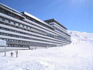 レ・メニュアールにあるStudio résidence Le Brelin aux MENUIRESの雪の人々が降る浜辺の大きな建物