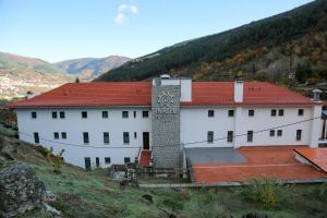 un bâtiment blanc avec un toit rouge sur une colline dans l'établissement INATEL Manteigas, à Manteigas