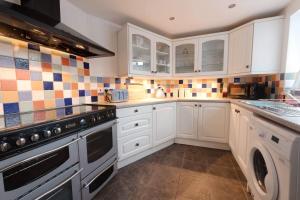 uma cozinha com armários brancos e um forno com placa de fogão em Platform 13 Railway Cottage em Conwy