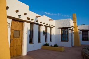 un edificio blanco con puerta y ventanas de madera en Olivares Rural, en Los Albaricoques