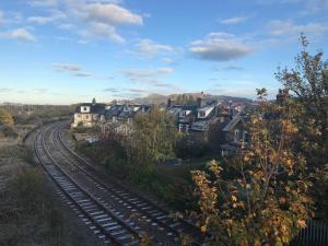 a train track next to a town with houses at Platform 13 Railway Cottage in Conwy