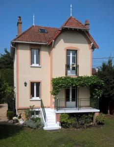 a house with a porch and a balcony at la villa des chats in Andrésy