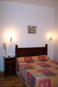 una camera da letto con un letto e un tavolo e una foto appesa al muro di Hôtel Central a Digne-Les-Bains