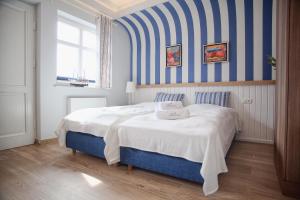 a bedroom with a bed with a blue and white striped wall at Mistral Ustka in Ustka