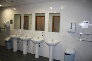 a bathroom with four sinks and mirrors on the wall at Albergue Ferramenteiro in Portomarin
