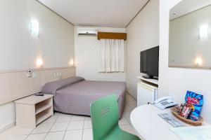 a hotel room with a bed and a desk at Hotel Expressinho Aeroporto in Porto Alegre