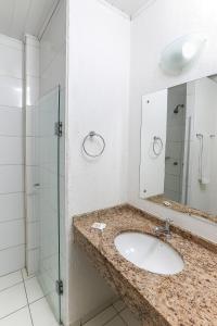 a bathroom with a sink and a glass shower at Hotel Expressinho Aeroporto in Porto Alegre