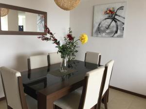 una mesa de comedor con sillas y un jarrón de flores en Costa Mansa II, Avenida Costanera 3100 , Departamento 2201, en Coquimbo