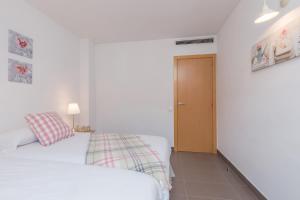 a white bedroom with two beds and a door at Apartamentos Cornellalux 2 in Cornellà de Llobregat
