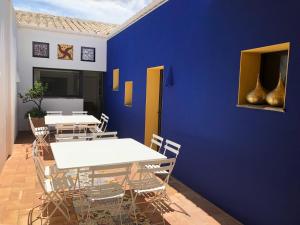 a dining room with white tables and chairs against a blue wall at Casa del Capitan in Cadaqués