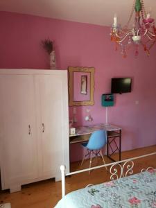 a bedroom with a pink wall with a desk and a chair at NOOR Apartment and Room in Hvar