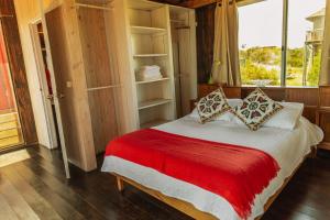 um quarto com uma cama com um cobertor vermelho e uma janela em BDL Beach Design Loft One em José Ignacio