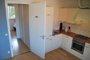 eine kleine Küche mit weißen Schränken und einem Waschbecken in der Unterkunft Wijnberg Appartementen in Hollum