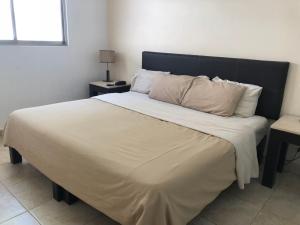 a bedroom with a large bed with a black headboard at Suites Real Tabasco in Villahermosa